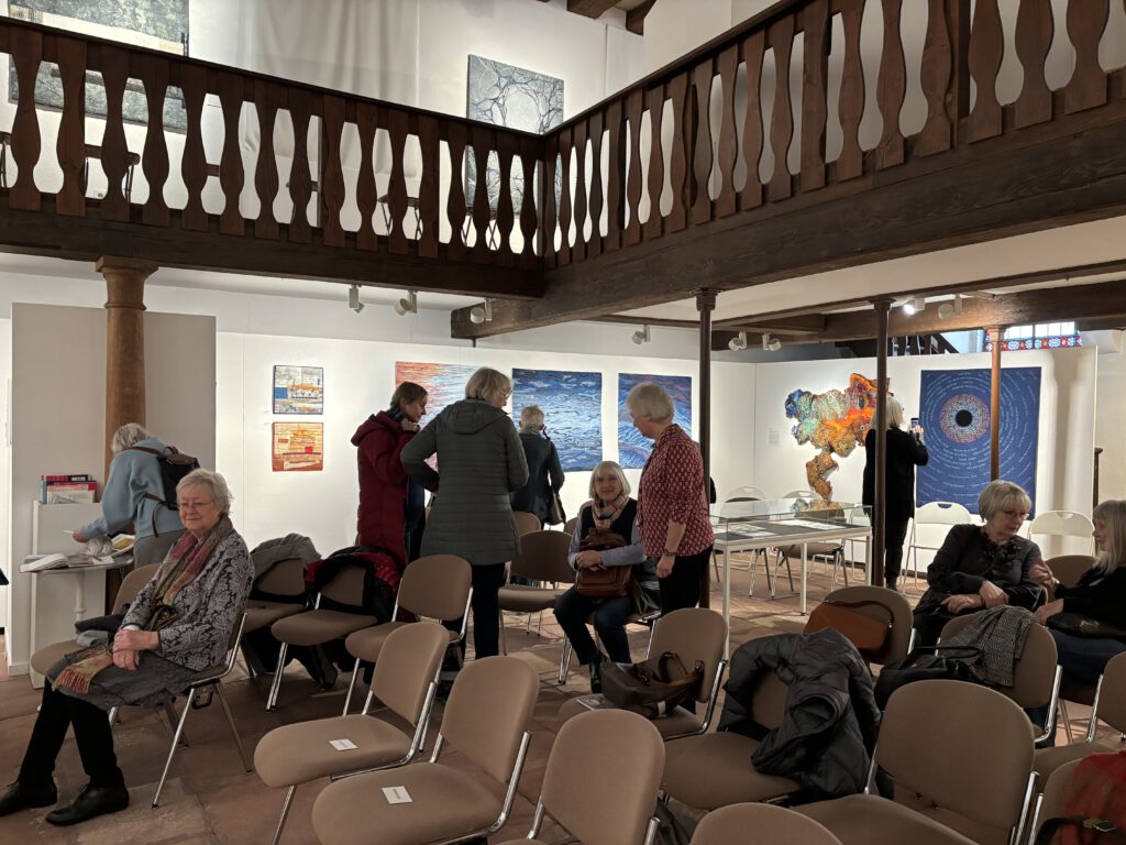 Besucher stehend und sitzend auf einer Vernissage.