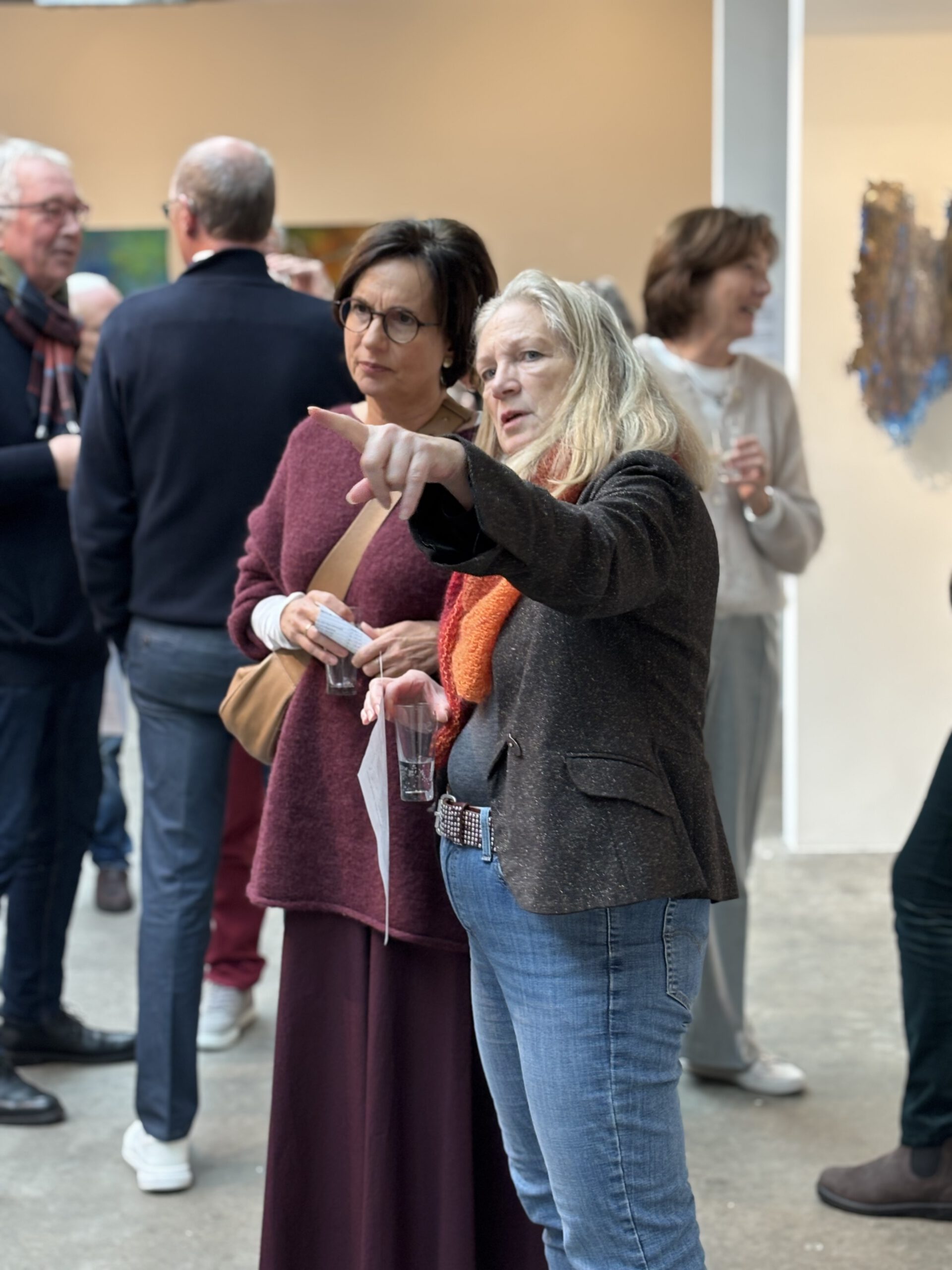 Besucher in einer Galerie betrachten Kunstwerke an der Wand.