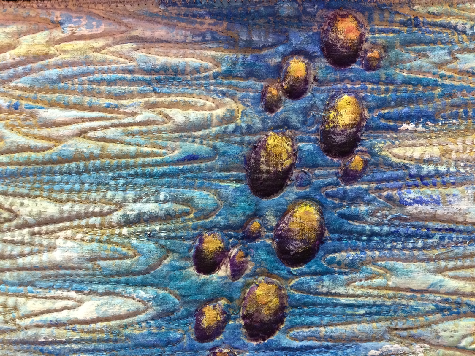 Bemalter Quilt mit blauen und braunen Strukturen und eingearbeiteten Kugeln