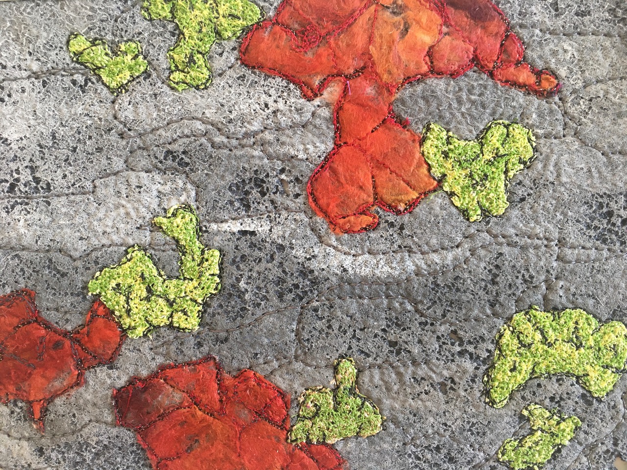 Abstrakte, dunkle Linien, die wie kahle Zweige wirken, auf einem hellblau-grün verlaufenden Textilhintergrund.