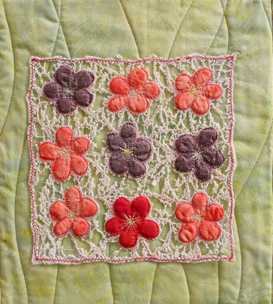 Dekorative textile Fläche mit kleinen roten Blütenelementen.