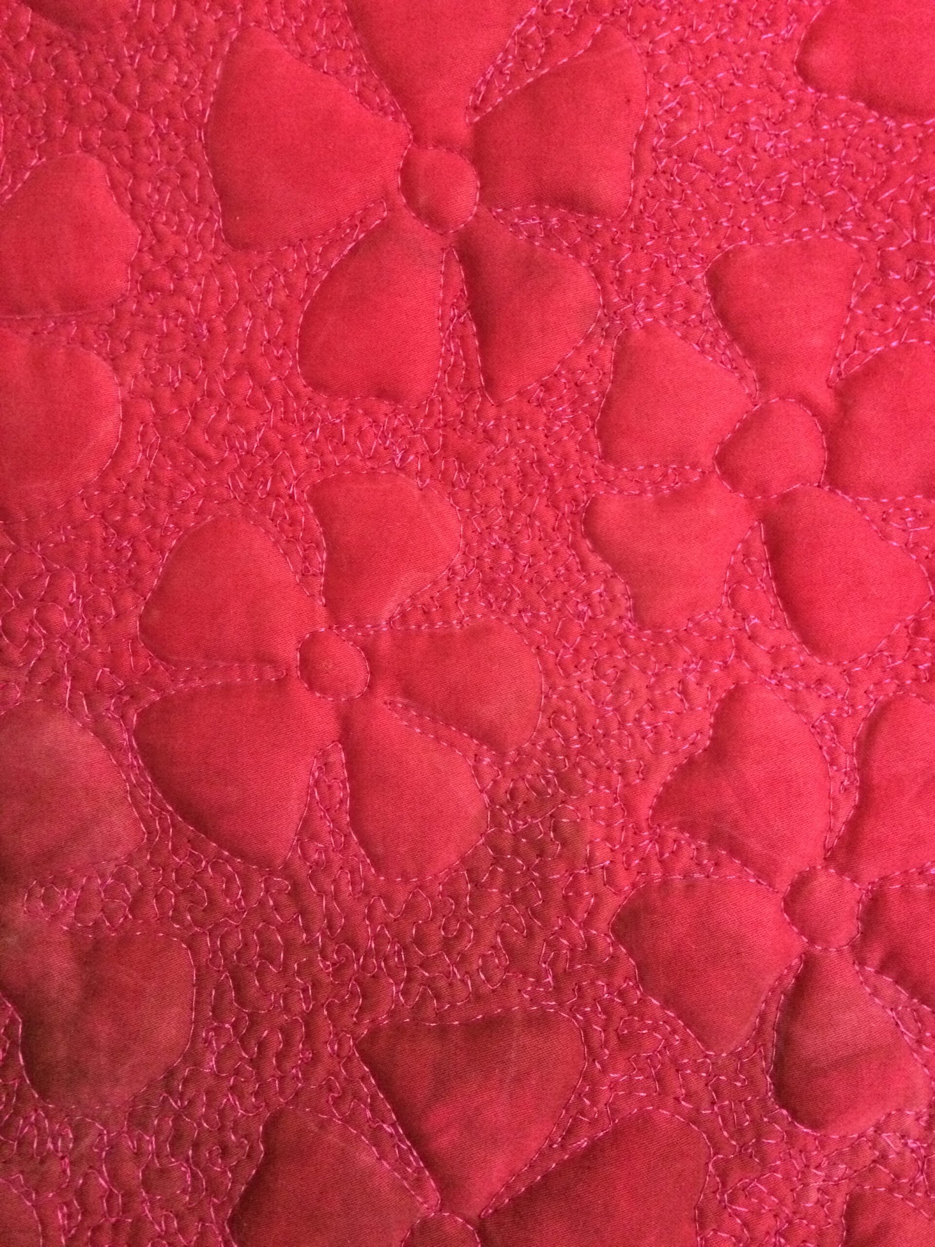 Ein leuchtend pinker Quilt mit erhabenen, blumenförmigen Polsterstrukturen.